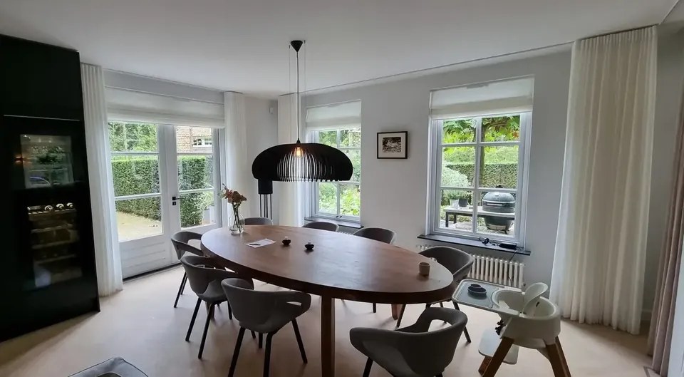 Lichte eetkamer met grote ramen en gordijnen